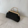 Elegante borsa a conchiglia nera intrecciata con manico floreale dorato e chiusura vintage - Nero