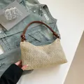 Beige gewebte Stroh-Tragetasche mit braunen Ledergriffen auf einer Jeansjacke - Braun