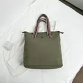 Olive green tote bag with large eyes design and striped handles for casual travel - Green