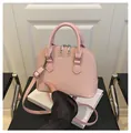 Pale pink shell-shaped handbag with woven texture and metallic brand lettering details - Pink