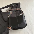 Borsa a tracolla nera lucida con tracolla larga colorata in stile etnico e fibbia - Nero