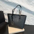 Classic black tote bag with grey monogram print and gold M charm on a stone background - One Size / Black