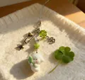 Detail van pluche puppy hanger met klavertje en ster hanger op zachte witte stof - Telefoonkoord Stijl