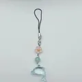 Detail eines süßen blauen Delfin-Anhängers mit Blumenperlen an einem Schlüsselband - Hautfarben