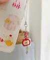 Vista macro di un ciondolo per telefono fatto a mano con mela rossa e quadrifoglio - Stile Mela Perlina Gialla Quadrifoglio (A)