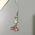 Dettaglio di un ciondolo per telefono con fragola, cuore rosa e perline floreali bianche - Ciliegia Rosa