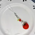 Cute red tomato beaded charm with heart and star accents on white decorative plate - Tomato