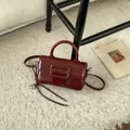 Detail of a vintage burgundy leather mini handbag with a square buckle and heart charm - Wine Red with Pendant