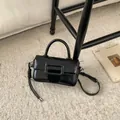 Detail view of the black glossy mini square bag with woven strap and large square buckle - Black With Pendant