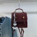 Minimalist burgundy backpack with white stitching and dog charm shown in 2025 winter style - Wine Red With Pendant