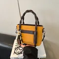 Fashionable ginger yellow and brown leather tote with woven circular handle and charms - Brown