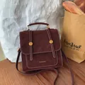 Zaino vintage in pelle rosso scuro con finiture dorate su tavolo in legno - Rosso Vino Senza Pendente