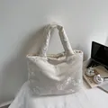 Elegant beige satin tote bag with floral embroidery on desk with laptop and art book - White