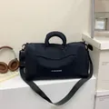 Detalle de bolsa de viaje negra en oxford con etiqueta lateral y correa de hombro ajustable - Negro