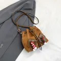 Brown suede drawstring bucket bag with dual front pockets and festive pompom charms - Brown