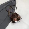 Deep brown suede bucket bag with festive pom-pom charms and leather crossbody strap - Brown
