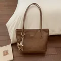 Detail view of large brown PU leather tote bag with plush charm and brand logo - Brown with Pendant