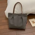 Minimalist canvas tote bag in dark grey with brown handles on a wooden floor - Dark Brown