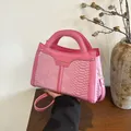 Makroaufnahme der rosa Schlangenleder-Prägung und des runden Griffs der Tasche - Rosa