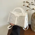 Detail der weißen Crossbody-Tasche mit Krokodilmuster und goldenem Logo-Schriftzug - Weiß