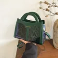 Close-up of dark green faux snake texture and glossy patent leather on a small square bag - Green