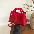 Detail der roten Handtasche mit Schlangenprägung und goldener Modeaufschrift - Rot