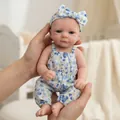 Realistic 12 inch reborn baby doll in blue floral romper held in palm of hands - Blue Floral / 30 cm