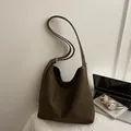 Large dark brown suede hobo bag with adjustable strap in a lifestyle setting - Green