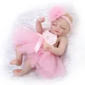 Lifelike reborn baby doll in pink tutu dress and floral headband on white faux fur - Pink / 26cm