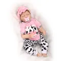 Realistic reborn baby doll in pink cow print outfit sleeping on white plush blanket - Pink Cow Outfit (Pink) / 55 cm