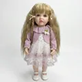 Lebensechte 22-Zoll Reborn-Puppe Betty mit blondem Haar und lila Strickjacke mit Kleid - Vollvinyl Großer Stil / Lila und Weiß