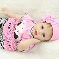 Lifelike reborn baby doll in pink cow print outfit with matching floral headband - 55 cm / Pink Cow Style