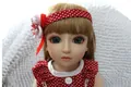 Primer plano de muñeca BJD con pelo rubio, ojos azules y diadema roja con lunares blancos - Muñeca de pelo marrón / 45cm