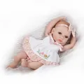Lebensechte Reborn Puppe im rosa gepunkteten Prinzessinnenkleid auf weißem Plüsch - Offene Augen Stil