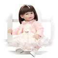 Realistic reborn baby girl doll in pink knit cardigan and floral dress on garden bench - 52cm / Straight
