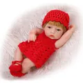 Mini soft silicone newborn doll in handmade red knit outfit on white plush carpet - Red