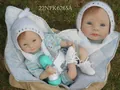 Realistische Reborn-Puppe mit blau gestreiftem Outfit und grünem Fläschchen auf Rasen - Blau Gestreift (22NPK6265A) / 55 cm