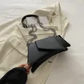 Modern black geometric crossbody bag with silver chain strap on a white tweed jacket - Black