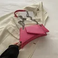 Pink crescent crossbody bag with silver chain strap on a white blazer background - Rose Pink