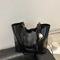 Glossy black large tote bag with baseball pendant charm on a leather sofa - With Pendant / Black