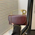 Schicke weinrote Ledertasche mit goldenem Büroklammergriff und Kettenriemen - Rot
