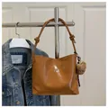 Detail van glanzende bruine leren tas met zilveren strik en een pluche beer bedeltje - Met Ornament / Bruin