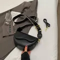 Black leather saddle bag with dual straps on white bedding for casual style - Black