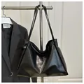 Primer plano de un bolso tote de cuero PU negro brillante con textura de grano fino - Negro