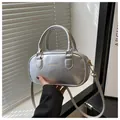 Detailed shot of a metallic silver mini handbag featuring an embossed Fashion & Bags logo - Silver