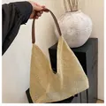 Nahaufnahme einer Strohtasche mit braunem Lederriemen vor minimalistischem Hintergrund - Braun