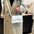 Elegant white square crossbody bag with unique wavy flap design and gold hardware - White