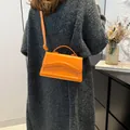 Orange PU leather crossbody bag with wavy flap and adjustable strap on a female model - Orange