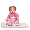 Realistic reborn baby doll in pink outfit with nursing bottle and pacifier on white mat - 55 cm / Pink Cat Outfit