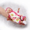 Mini reborn baby doll in pink elephant romper held in hand to show pocket size - Sleep Mode